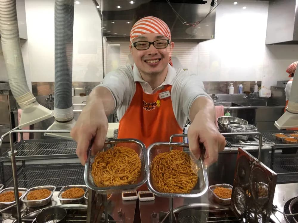 Man showing freshly fried ramen noodles at the Cup Noodles Museum in Yokohama, Kanagawa Prefecture